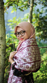 Portrait of smiling young woman standing in forest