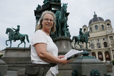 Portrait of woman holding map while standing against hofburg palace