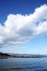 View of city at waterfront against cloudy sky