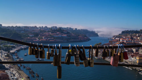 Close-up of padlocks hanging on sea at porto against sky