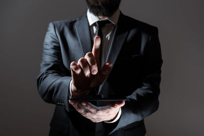 Midsection of businessman gesturing while standing against wall