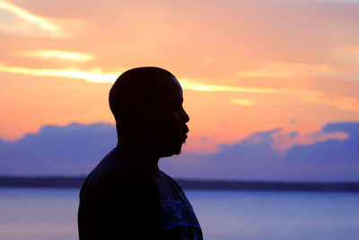 Side view of silhouette man standing against dramatic sky during sunset