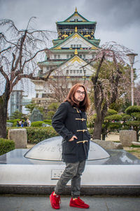 Portrait of smiling young woman standing against building