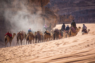 Group of people riding horse on desert