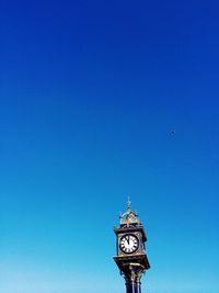 Low angle view of birds flying against clear blue sky