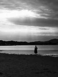 Silhouette man standing on beach against sky