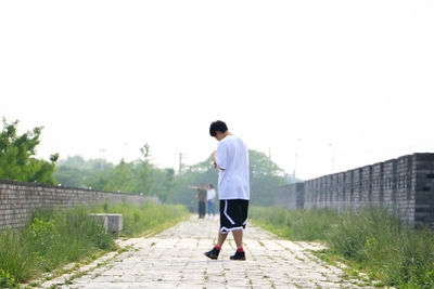 Full length of man walking on walkway against clear sky