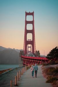 Rear view of people on bridge at sunset