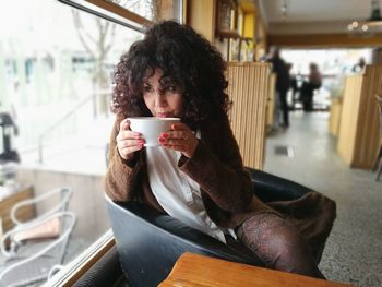 Young woman having drink while sitting in cafe
