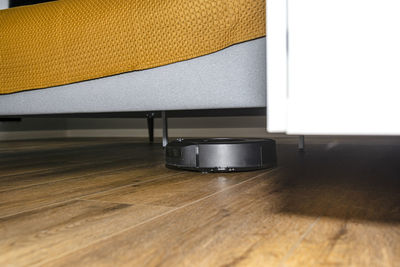 A modern robotic vacuum cleaner cleans vinyl panels under bedroom furniture. 