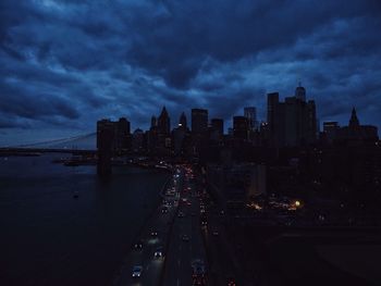 Illuminated cityscape against cloudy sky