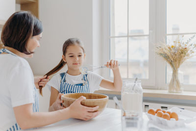 Mother with daughter preparing food in kitchen