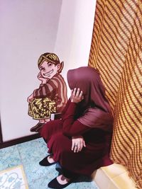 Woman sitting on wall at home