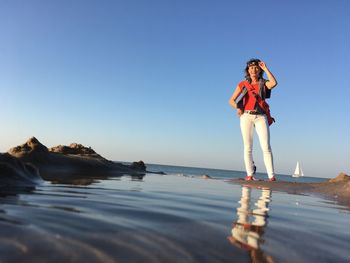 Woman standing in sea against clear sky