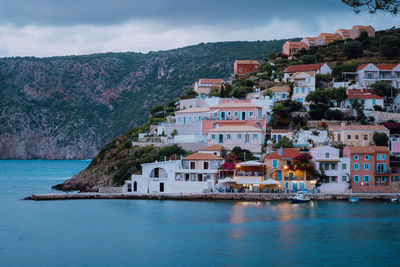 Buildings by sea against sky in town