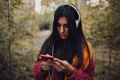 Young woman looking away while standing on tree