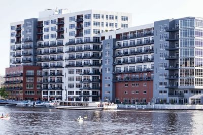 Buildings by river against sky in city