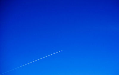 Low angle view of vapor trail against clear blue sky