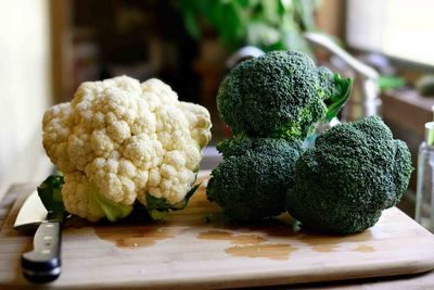 Broccoli and cauliflower with knife on cutting board