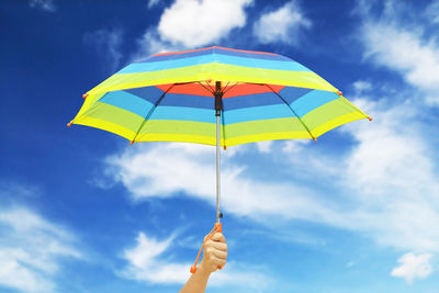 Low angle view of person holding umbrella against sky