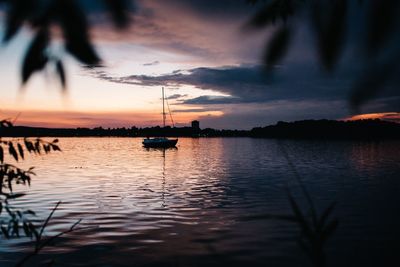 Silhouette sailboats in sea against sky during sunset