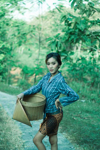 Full length of a beautiful young woman standing against plants