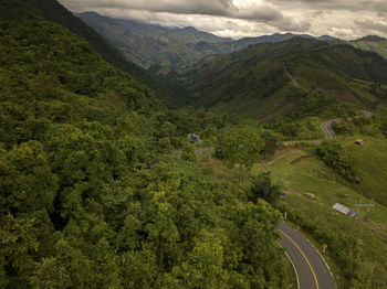 Aerial view of countryside road passing through the lush greenery tropical rain forest mountain