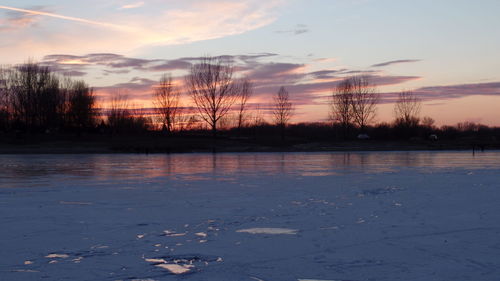 Scenic view of lake against sky at sunset