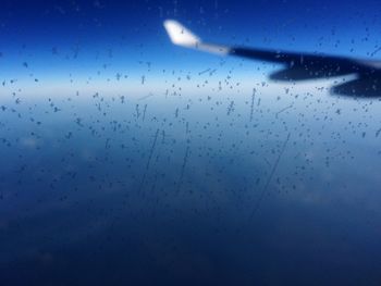 Full frame shot of wet window against blue sky