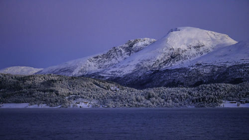 Scenic view of sea and snowcapped mountains against clear sky