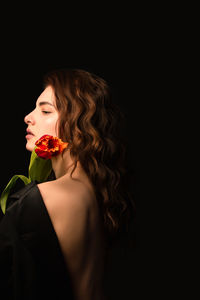 Close-up of young woman against black background