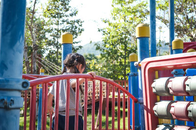 Rear view of woman sitting on slide at playground