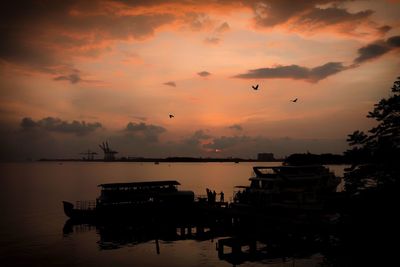 Silhouette boats in sea against sky during sunset