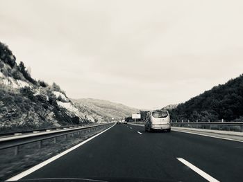 Vehicles moving on road against sky