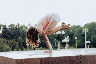 Side view of woman on rock against sky