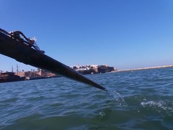 Built structure by sea against clear blue sky