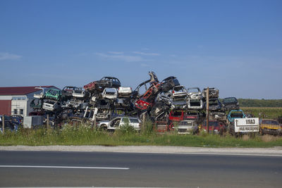 Abandoned cars on roadside against sky