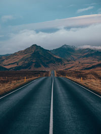 Road leading towards mountains against sky