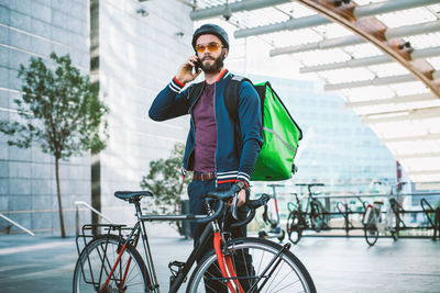 Man standing with bicycle on street in city