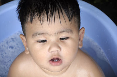 Close-up of shirtless cute baby boy in bucket