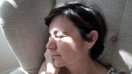Close-up of mature woman sleeping on sofa at home