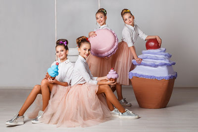 Portrait of girls with artificial ice cream against wall