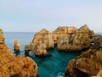 Rock formations in sea against clear blue sky