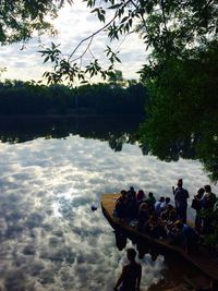People sitting by lake against sky