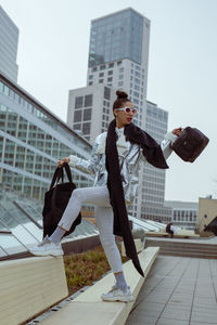 Full length of woman standing against buildings in city