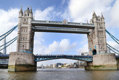 Low angle view of tower bridge over thames river against cloudy sky