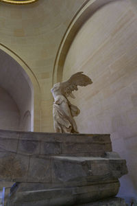 Low angle view of angel statue against historic building