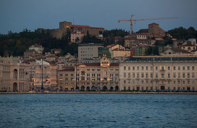 Buildings by river against sky