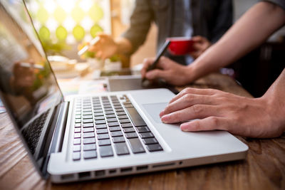 Midsection of woman using laptop on table