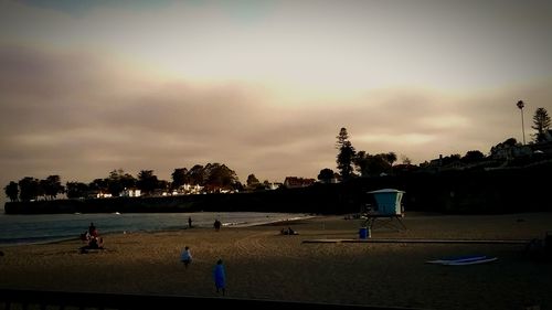 People on beach against cloudy sky